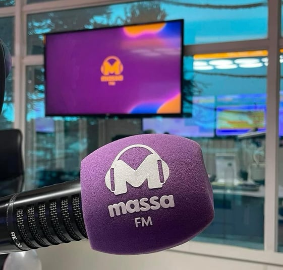 Estúdio de rádio com microfone com espuma roxa e logo com letra M e fone de ouvido