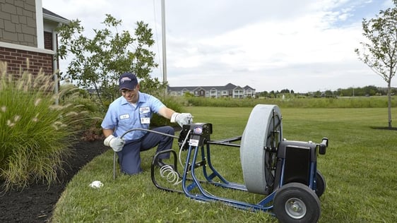 A man in a blue shirt is holding a hose