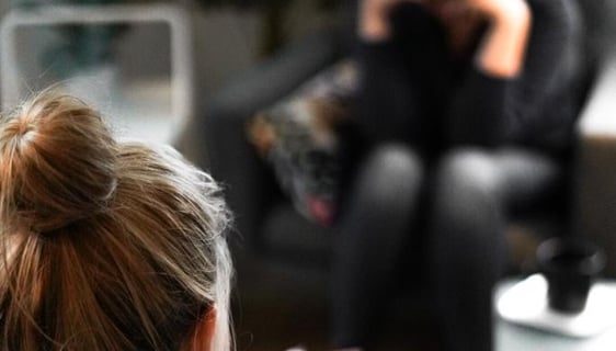 a woman sitting on a couch with a man in a chair