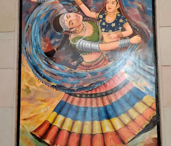 An artistic representation of two women engaged in a lively dance, set against a colorful wall.