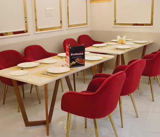 a table with a table setting with red chairs and gold accents