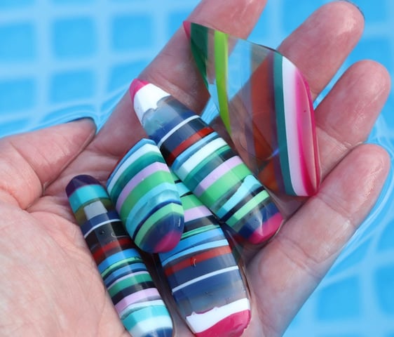 a hand holding a selection of surfite or surf stone cabochons in bright colours