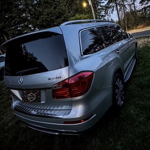 Silver Mercedes-Benz Bluetec SUV parked on a tree-lined driveway at dusk, showcasing perfection