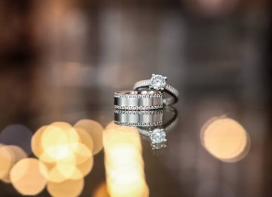 The image captures a stunning wedding ring set displayed on a reflective surface, creating a mirror-