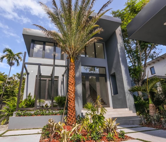 Modern Modular shaped house with palm trees and a gate and walkway