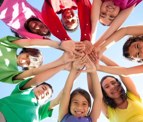 a group of people standing in a circle with their hands together