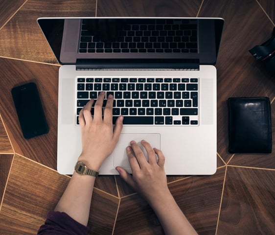 Top down view of a person working on a MacBook at a desk.