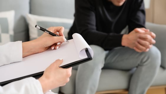 a man and woman sitting on a couch with a clipboard