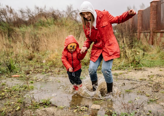 woman splashing in puddles with child