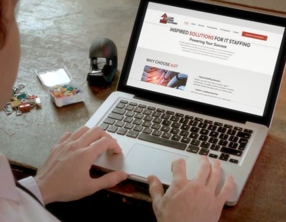 a man sitting at a desk with a laptop computer and a cell phone