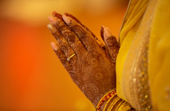 hindu woman praying with folded hands, has mehendi on hands