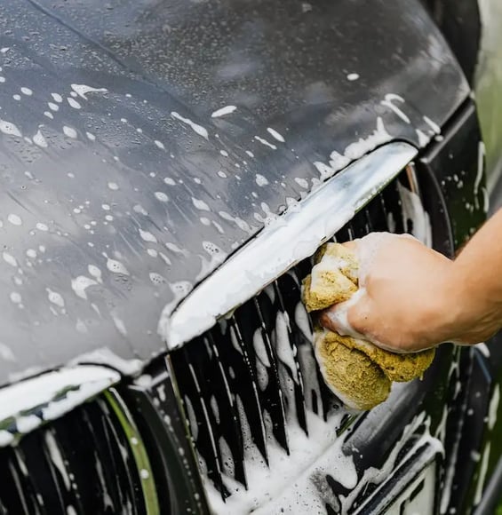 a person cleaning a car with a sponge pad