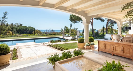 View from the shaded porch across the pool, with the Mediterranean Sea visible in the background.