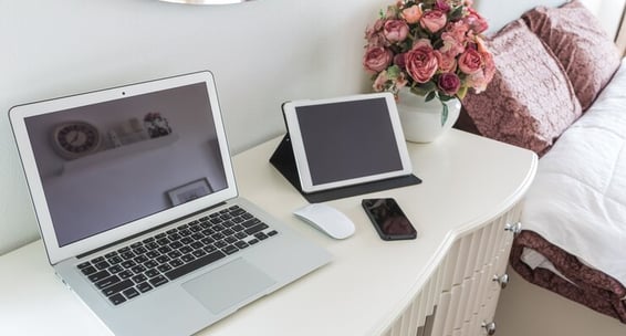 TechAid spec laptop computer sitting on a desk with a vase of flowers