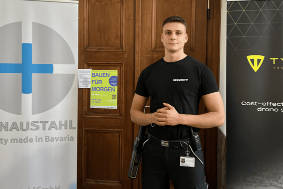 Eine Sicherheitskraft in "SECURITY"- Shirt vor einer Tür