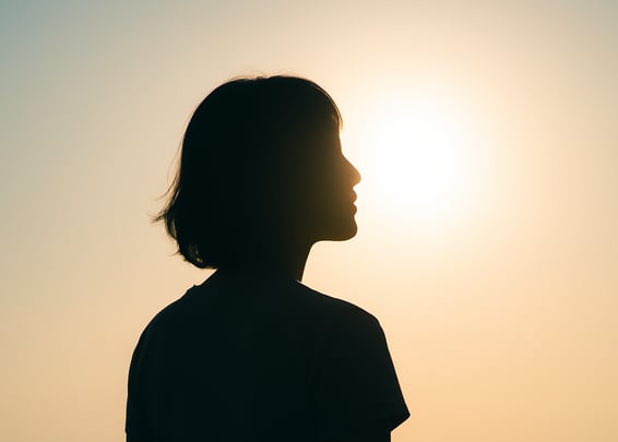 Imagen de perfil de una mujer.El sol está atrás de ella, no se nota su cara pero parece en reflexión