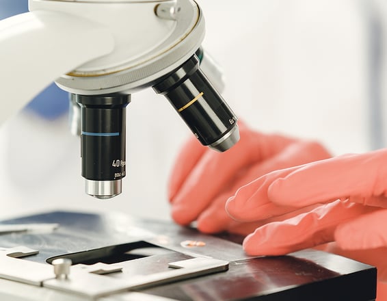 a person in a lab coat and gloves holding a microscope