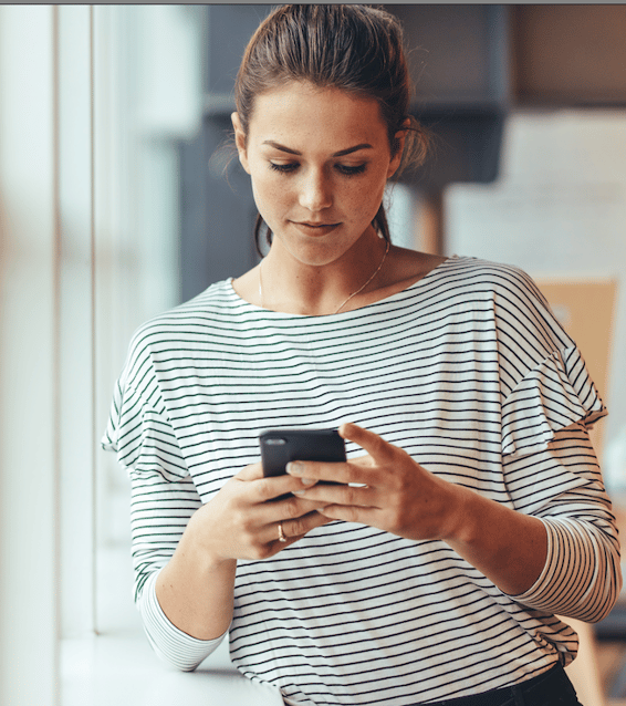 a woman in a striped shirt is looking at her phone