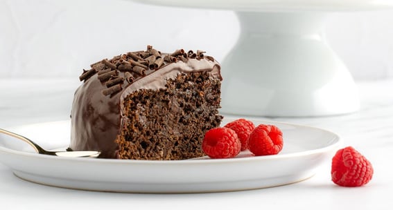 a slice of chocolate cake with chocolate frosting and raspberries