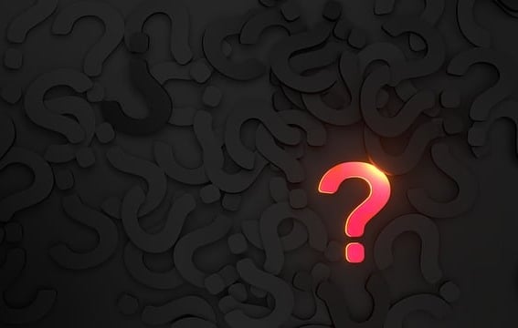 background of black question marks with single pink/ gold question mark in foregrounda question mark