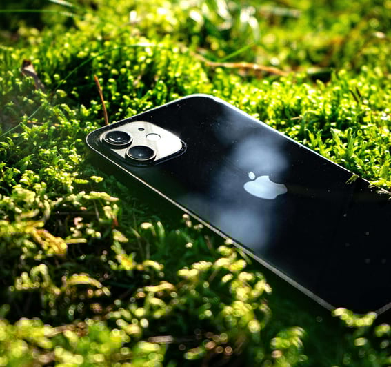 iPhone Km0 negro sobre musgo verde, destacando la sostenibilidad y la integración de la tecnología con la naturaleza.