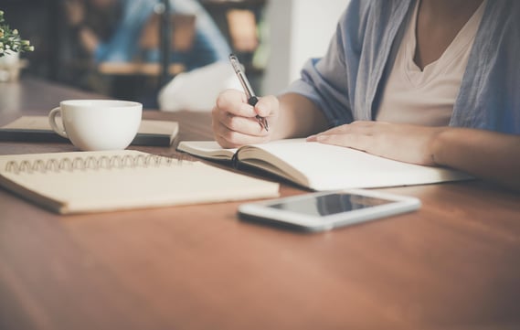 woman at a desk with notebook and coffee cup