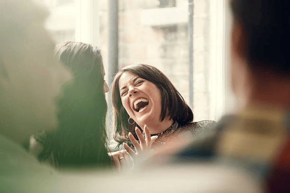 a woman laughing facing another women