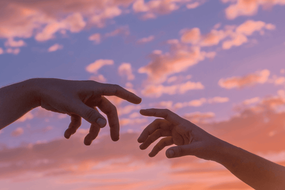 two hands reaching out to touch each other with clouds in the backdrop.