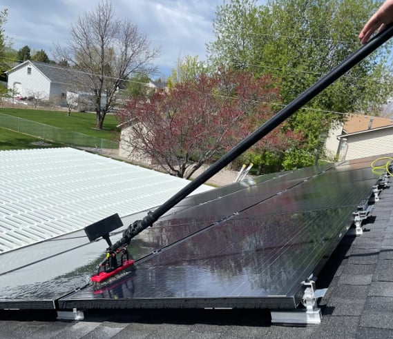 a man using a brush to clean solar panels