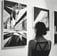 A person stands in an art gallery observing framed photographs mounted on the walls.