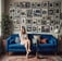 a woman in a room with a blue couch and lots of pictures on the wall