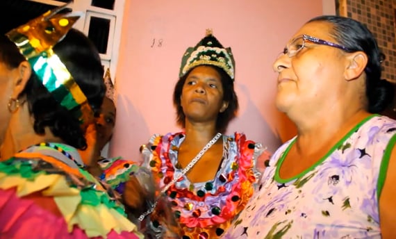 Mulheres do Reizado em trajes coloridos e coroa cantando durante festejo tradicional em São Tomé