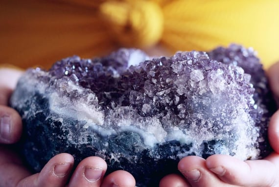 a purple Amethyst cluster crystal held in hands