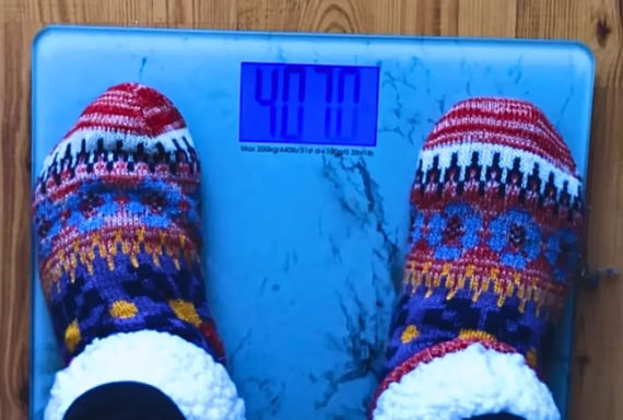 Feet standing on a weight scale representing weight loss moderation journey