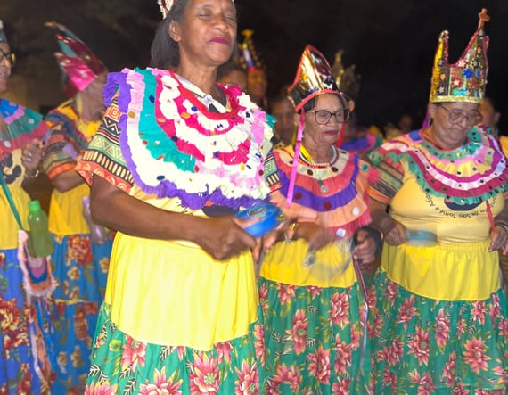 Ciganinhas dançando com roupas floridas e coroas, celebrando cultura e resistência quilombola