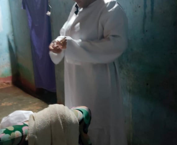 Pessoa vestida de branco se prepara para o ritual dos penitentes em ambiente simples e escuro