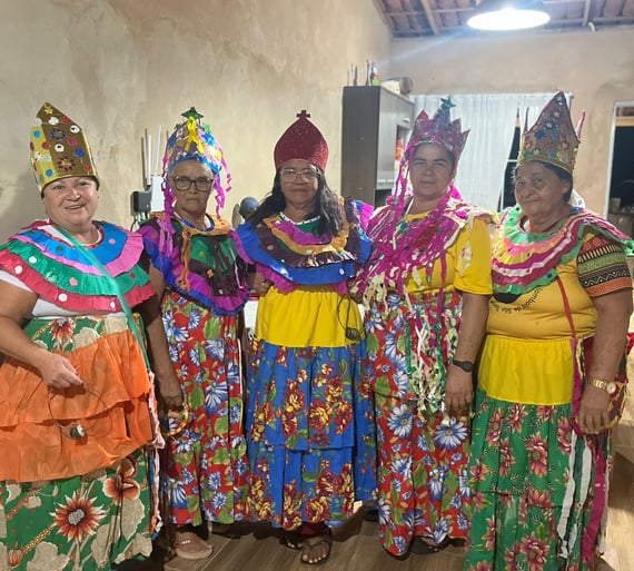 Ciganinhas com roupas coloridas, coroas e saias longas em ambiente interno, prontas para dançar