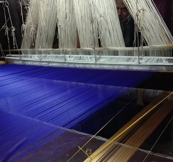 a man is working on a blue and white weaving machine