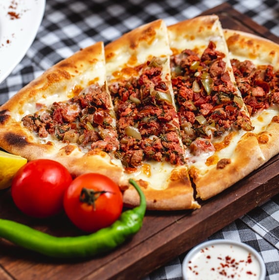 Esfiha aberta caseira com massa dourada e recheio de carne temperada, decorada com salsinha e limão,