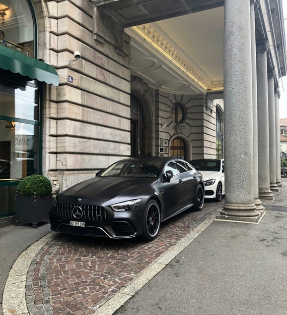 Two sports cars parked outside of an hotel