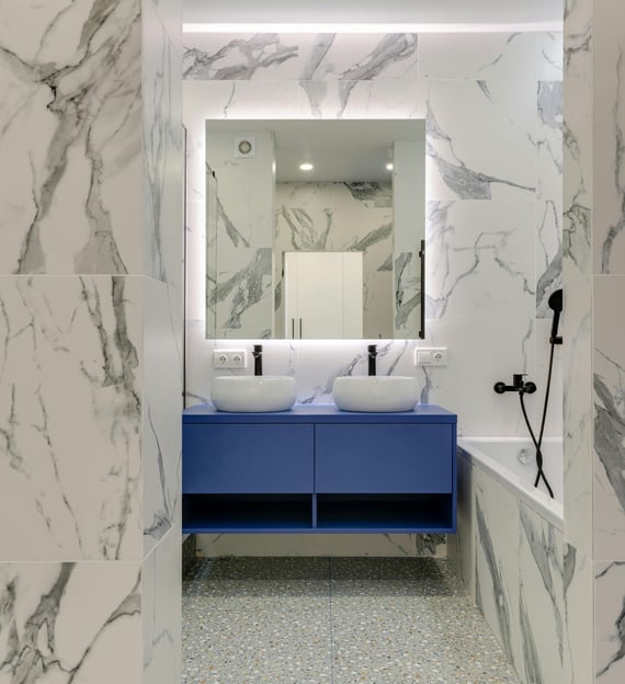 a bathroom with a marbled floor and a blue vanity