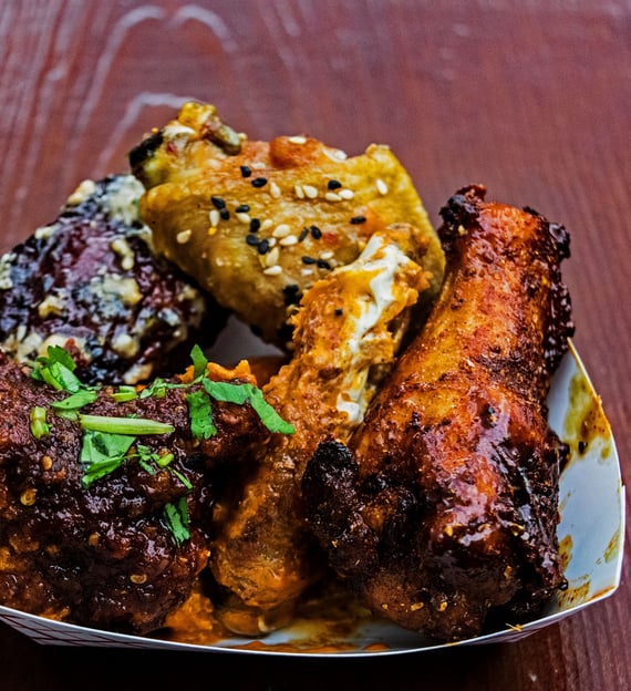 a plate of food with chicken wings and a side of corn