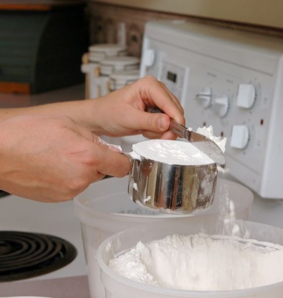 a person is holding a spoon and mixing a bowl of flour