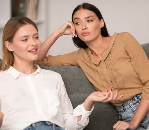 two women sitting on a couch talking to each other