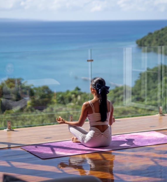 a woman sitting on a yoga mat in front of a large window