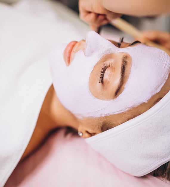 Vrouw met wit gezichtsmasker en handdoek over zich