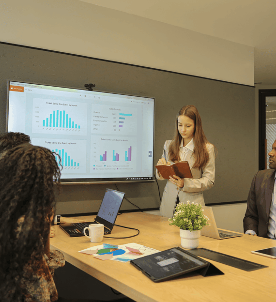 Team member presenting data analytics insights on a large screen in a conference room.