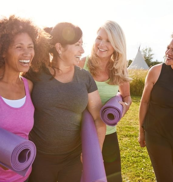 a group of women holding yoga mats and smiling