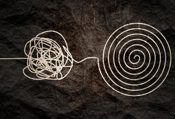 black and white image.  piece of string, tangled on one side, perfectly coiled on the other