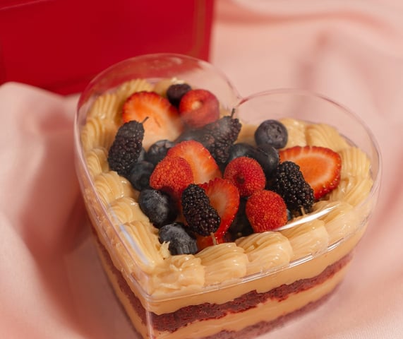 a heart shaped cake with fruit on top of it